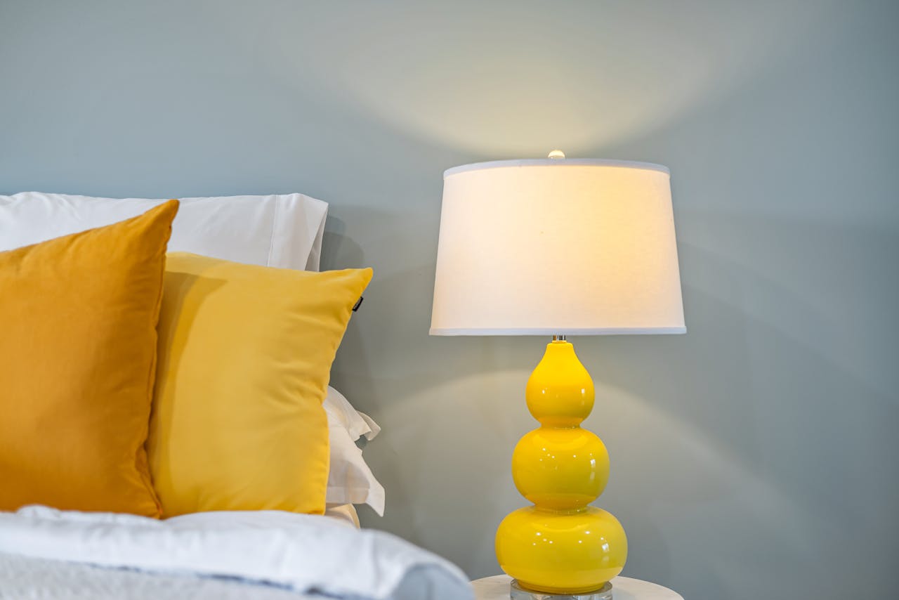 Cozy bedroom interior featuring yellow accents and a chic bedside lamp for a warm ambiance.